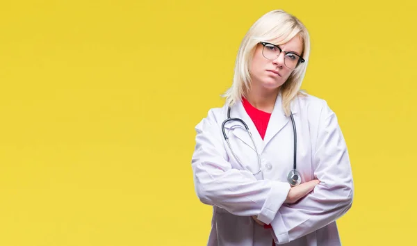 Young beautiful blonde doctor woman wearing medical uniform over isolated background skeptic and nervous, disapproving expression on face with crossed arms. Negative person.