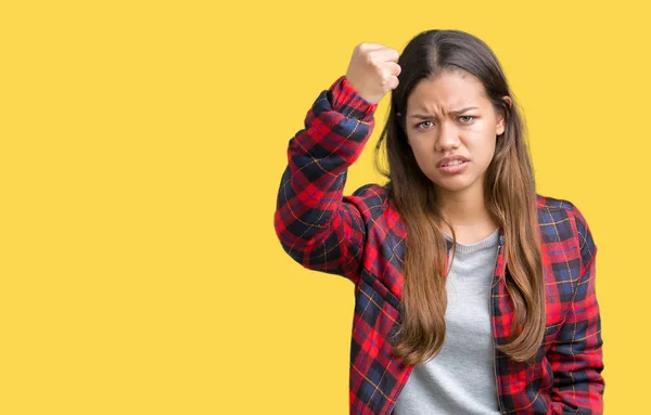 Young beautiful brunette woman wearing a jacket over isolated background angry and mad raising fist frustrated and furious while shouting with anger. Rage and aggressive concept.