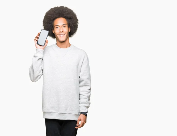 stock image Young african american man with afro hair showing smartphone screen with a happy face standing and smiling with a confident smile showing teeth