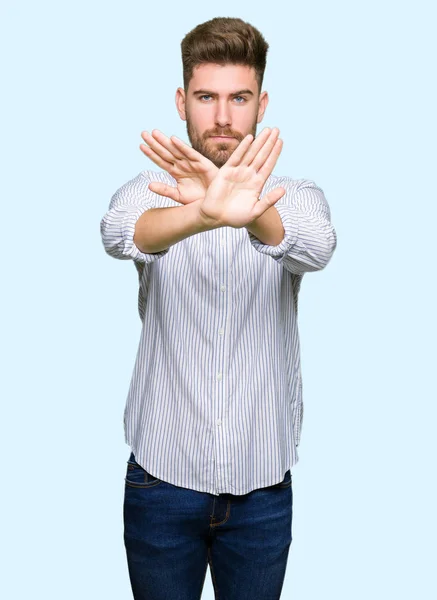 Young handsome man Rejection expression crossing arms and palms doing negative sign, angry face