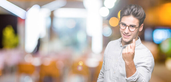 Young handsome man wearing glasses over isolated background Beckoning come here gesture with hand inviting happy and smiling