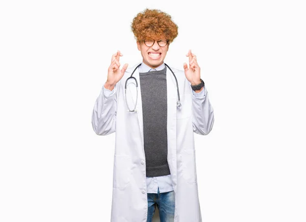 Joven Médico Guapo Con Abrigo Médico Sonriendo Cruzando Los Dedos — Foto de Stock