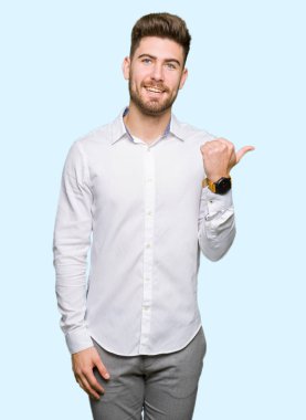 Seyir ve başparmak yanında yukarıyı mutlu yüz ile gülümseyen genç yakışıklı iş adamı.