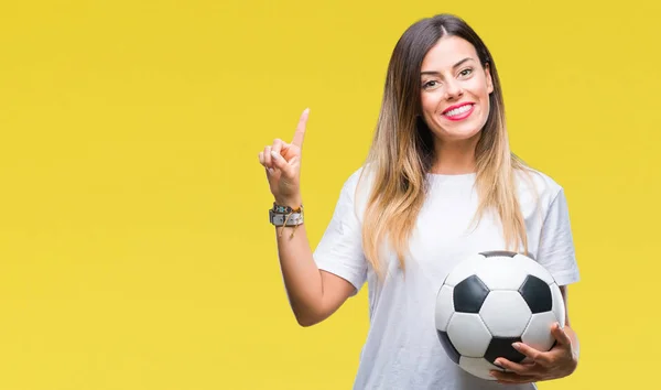 Young beautiful woman holding soccer ball over isolated background surprised with an idea or question pointing finger with happy face, number one