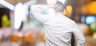 İzole arka plan geriye düşünme hakkında şüphe kafasına el ile üzerinden sweatshirt giyen genç yakışıklı adam