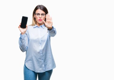 Genç güzel iş kadın gösteren boş ekran smartphone açık eliyle dur işareti ile ciddi ve kendine güvenen ifade, savunma jest yapıyor izole arka plan üzerinde