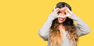 Kış elbise yapıyor kalp şekli ile el ve parmak işareti seyir gülümseyen genç güzel kadın