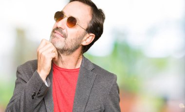 Orta çağda yakışıklı iş adamı, çenesi el ile gözlük takan soru hakkında düşünme, dalgın ifade. Düşünceli bir yüz ile gülümsüyor. Şüphe kavramı.