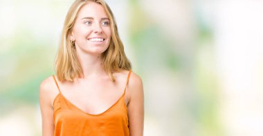 Uzak tarafına yüzünde, doğal ifade gülümseme ile seyir izole arka plan üzerinde turuncu gömlek giymiş güzel ve genç birbayan. Kendine güvenen gülüyor.