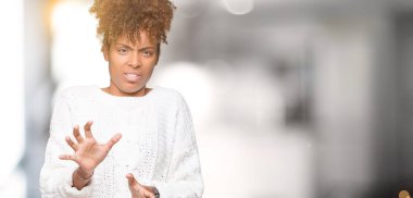 İzole arka plan üzerinde kış kazak giyen güzel genç Afro-Amerikan kadın tiksinti ifadesi, memnun ve korkulu tiksinti yüz yapıyorsun çünkü nefret tepki. Elleriyle kaldırdı. Sinir bozucu kavramı.