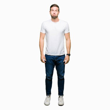Komik surat ile rahat beyaz t-shirt şişirme yanakları giyen yakışıklı adam. Ağız ile hava, deli ifade şişirilmiş.