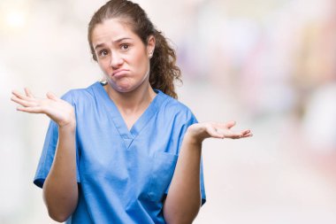 İzole arka plan clueless ve şaşkın bir ifadeyle kollar ve eller kaldırdı üzerinde hemşire ya da cerrah üniforma giyen genç esmer doktor kız. Şüphe kavramı.