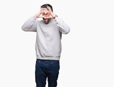 İzole arka plan yaparken kalp şekli el ve parmak işareti seyir gülümseyen ile üzerinden sweatshirt giyen genç yakışıklı adam
