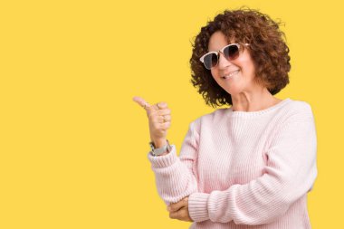 Yanına bir jest yapıyorsun gülümseyen pembe kazak ve güneş gözlüğü izole arka plan gurur, seyir üzerinde giyen güzel orta ager üst düzey kadın yaşasın