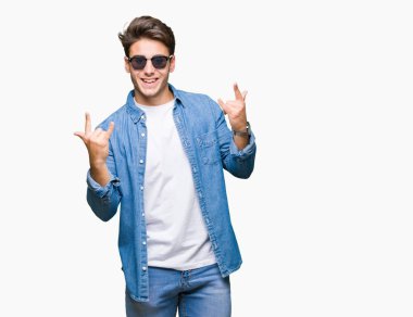 Genç yakışıklı adam deli ifade rock simge elle yapıyor ile bağırarak izole arka plan üzerinde güneş gözlüğü takıyor. Müzik yıldızı. Ağır kavramı.