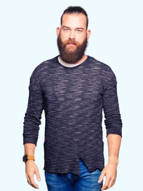 Genç Sarışın yüzünde ciddi bir ifade ile rahat kazak giyen adam. Basit ve doğal kameraya bakıyor.