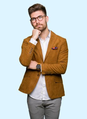 Gözlüklü el ile çene düşünme hakkında soru, dalgın ifade üzerine genç yakışıklı iş adamı. Düşünceli yüzüyle gülümsüyor. Şüphe kavramı.