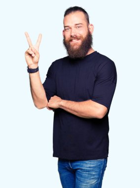 Genç Sarışın giyiyor rahat t-shirt mutlu yüz zafer işareti yaparken kameraya göz kırpıyor ile gülümseyen adam. İki numaralı.