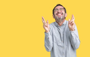 Umut ve gözleri kapalı geçiş parmaklarıyla gülümseyen izole arka plan üzerinde gözlük takan yakışıklı orta yaş zarif komuta sizde. Şans ve batıl kavramı.