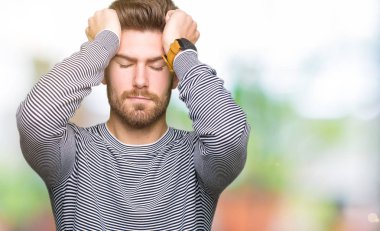 Genç yakışıklı adam giyen çizgili süveter çünkü umutsuz ve stresli baş ağrısı acı acı ve migren. Ellerini kafasına.