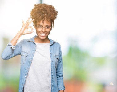 İzole arka plan el ve parmaklar ok işaretiyle yapıyor olumlu gülümseyen üzerinde gözlük güzel genç Afro-Amerikan kadın. Başarılı ifade.