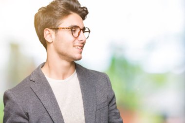 İzole arka plan uzak tarafına gülümseme ile yüzünde, doğal ifade bakmaktan gözlüklü genç iş adamı. Kendine güvenen gülüyor.