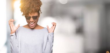 Arka plan deli kutluyor güzel genç Afro-Amerikan kadın üzerinde güneş gözlüğü takıyor izole ve crazy arms ile başarı için kaldırdı ve heyecanlı çığlık gözler kapalı. Kazanan kavramı