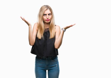 Genç güzel sarışın ve mavi gözlü kadın izole arka plan clueless ve şaşkın bir ifadeyle kollar ve eller kaldırdı. Şüphe kavramı.