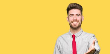 Tebrik ve konuksever dost sunan karşılıklı gülümseyen genç yakışıklı iş adamı. Başarılı iş.