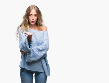 Bir öpücük el ile güzel ve seksi olmak hava üfleme kamera bakarak izole arka plan üzerinde kış kazak giyen güzel genç sarışın kadın. Aşk ifade.