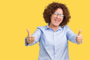 El ile pozitif jest yapıyor onaylama izole arka plan üzerinde gözlük güzel orta ager üst düzey businees kadın başparmak gülümseyen ve başarı için mutlu. Kamera, kazanan jest arıyorsunuz.