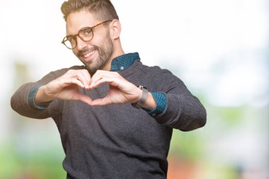 Kalp simgesi ve elleriyle şekil gösterilen aşık gülümseyen izole arka plan üzerinde gözlük takan yakışıklı delikanlı. Romantik kavramı.