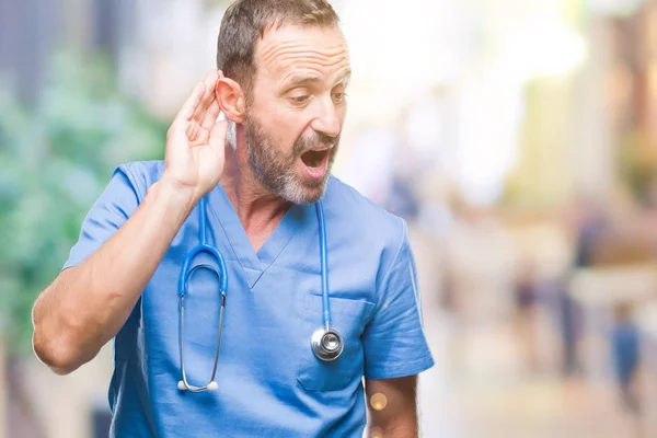 噂やゴシップに審理をリスニングの耳に手を浮かべて隔離された背景に医療制服を着て中年白髪の先輩医師の男 難聴の概念 — ストック写真