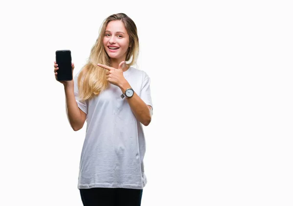 年轻美丽的金发女子显示屏幕的智能手机在孤立的背景非常愉快的指着手和手指 — 图库照片