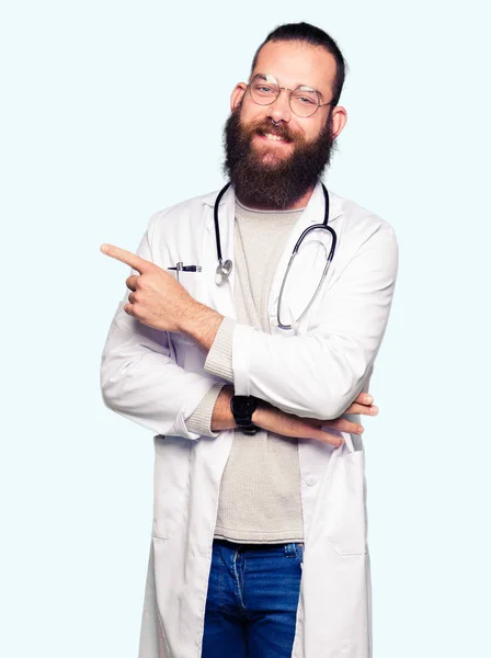 ひげ着て医療と若いブロンド医師男側表示広告 深刻な穏やかな顔に手指で指すをコートします — ストック写真