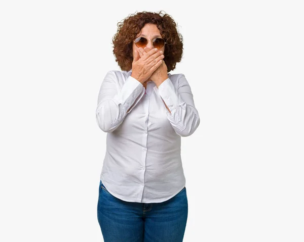 美しい中間エイガー シニア ビジネス女性がミスのため手で口を覆っているショックを受けて孤立の背景の上にサングラスをかけています 秘密の概念 — ストック写真