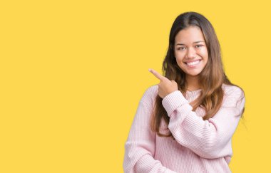 İzole arka neşeli bir gülümseme ile yüz el ve parmak kadar mutlu ve doğal ifade yüzünde yanında işaret içinde pembe kış kazak giyen genç güzel esmer kadın