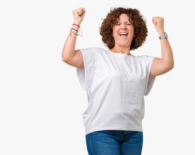 Zafer kutluyor gülümseyen izole arka kolları olan başarı için heyecan üzerinde beyaz t-shirt giyen güzel orta ager üst düzey kadın kaldırdı. Kazanan kavramı.