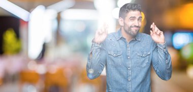 Yakışıklı delikanlı geçiş parmakları umut ve gözleri kapalı ile gülümseyen izole arka plan üzerinde. Şans ve batıl kavramı.