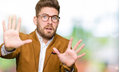 Şokta bağırarak korkuyor ve dehşet korku ifade dur hareketi el ile ile gözlüklü genç yakışıklı iş adamı. Panik kavramı.