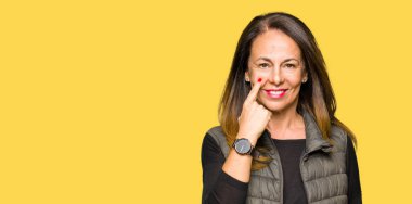 Kış yelek giyen güzel orta yaş kadın sizi jest izlerken göz Işaret, şüpheli ifade