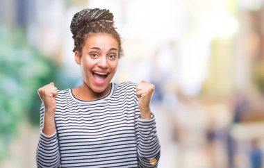 Üzerinde kazak giyen genç örgülü saç Afro-Amerikan Kız şaşırmış ve başarı için hayran kaldırdı kollarını açarak kutlama arka plan izole ve gözleri açık. Kazanan kavramı.