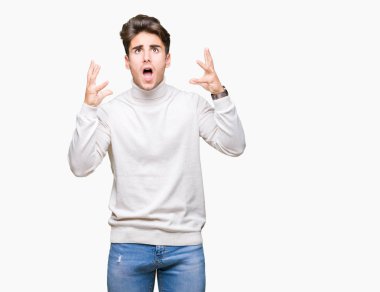 Genç yakışıklı adam izole arka plan üzerinde balıkçı yaka kazak giyiyor çılgın ve deli çığlık ve agresif ifade ve silah ile bağırdı kaldırdı. Hayal kırıklığı kavramı.