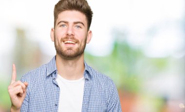 Casual Gömlek işaret parmağı ile başarılı fikir giyen genç yakışıklı sarışın adam. Çıktıktan ve mutlu. Bir numara.