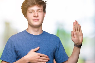 İzole arka plan üzerinde mavi t-shirt giyen genç yakışıklı adam göğüs ve açık palmiye el ile küfür, sadakat vaat yemini yapma