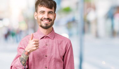 Hareketi el ile mutlu yaşasın yapıyor izole arka plan üzerinde pembe gömlek giymiş yakışıklı delikanlı. Başarı gösteren kameraya bakarak ifade onaylama.