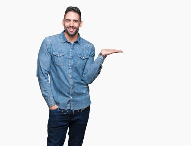 Genç yakışıklı adam neşeli sunulması ve kameraya bakarak avucunun ile işaret gülümseyen izole arka plan üzerinde.