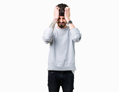 Genç yakışıklı adam kazak giyiyor çünkü umutsuz ve stresli baş ağrısı acı izole arka plan üzerinde ağrı ve migren. Ellerini kafasına.