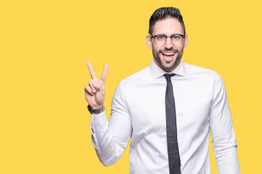 Mutlu yüz zafer işareti yaparken kameraya göz kırpıyor ile gülümseyen izole arka plan üzerinde gözlük takan genç yakışıklı iş adamı. İki numaralı.