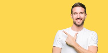Yakışıklı adam neşeli bir gülümseme ile el ve parmak kadar yan yüzünde mutlu ve doğal ifade ile işaret yüz ile rahat beyaz t-shirt giyen